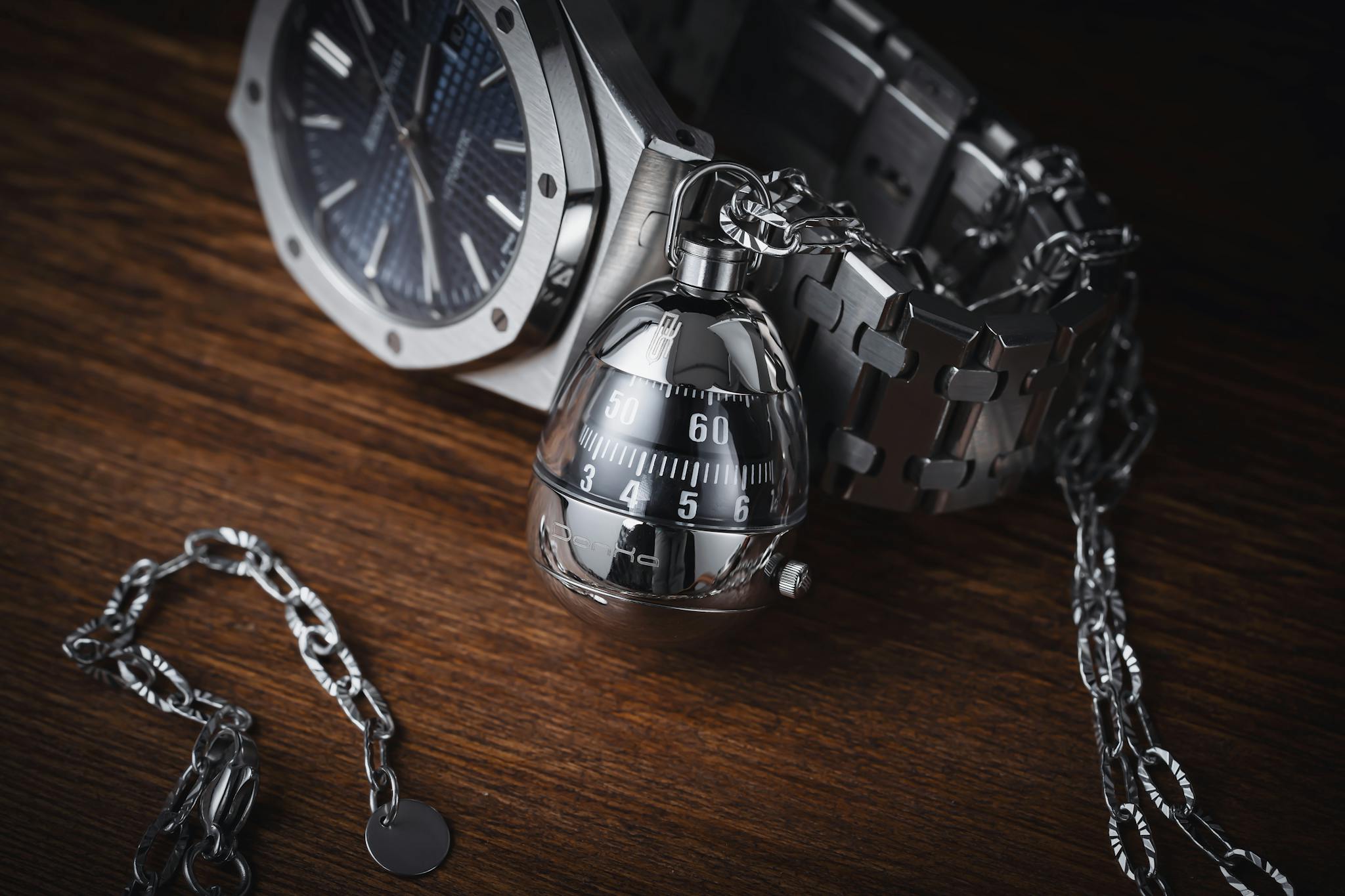 Sophisticated stainless steel watch and chain on wooden surface, highlighting elegance and luxury.